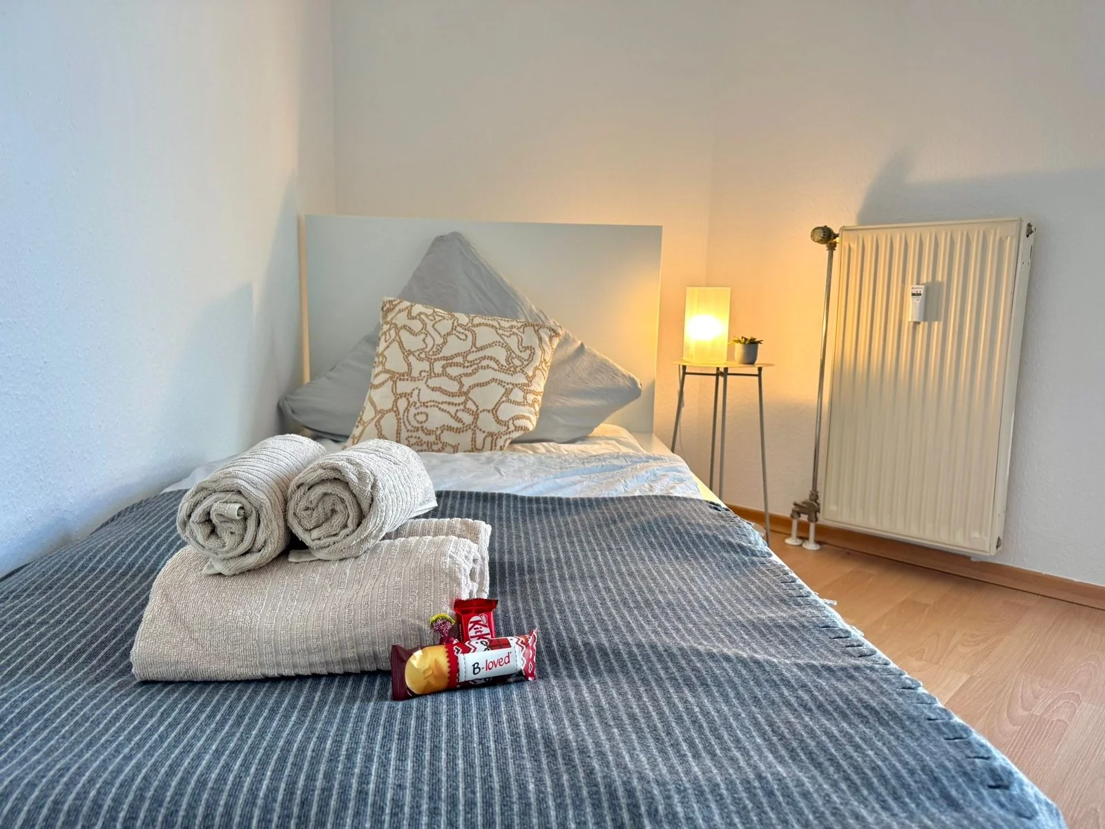 Airbnb-Übergabereinigung in Grevenbroich: frisch bezogenes Doppelbett mit gerollten Handtüchern und Welcome-Gruß für die nächsten Gäste, ausgeführt von bludau Gebäudereinigung